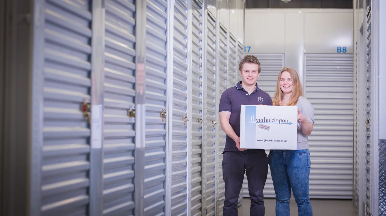 Klanten met hun JL-verhuisdoos tussen de opslagunits