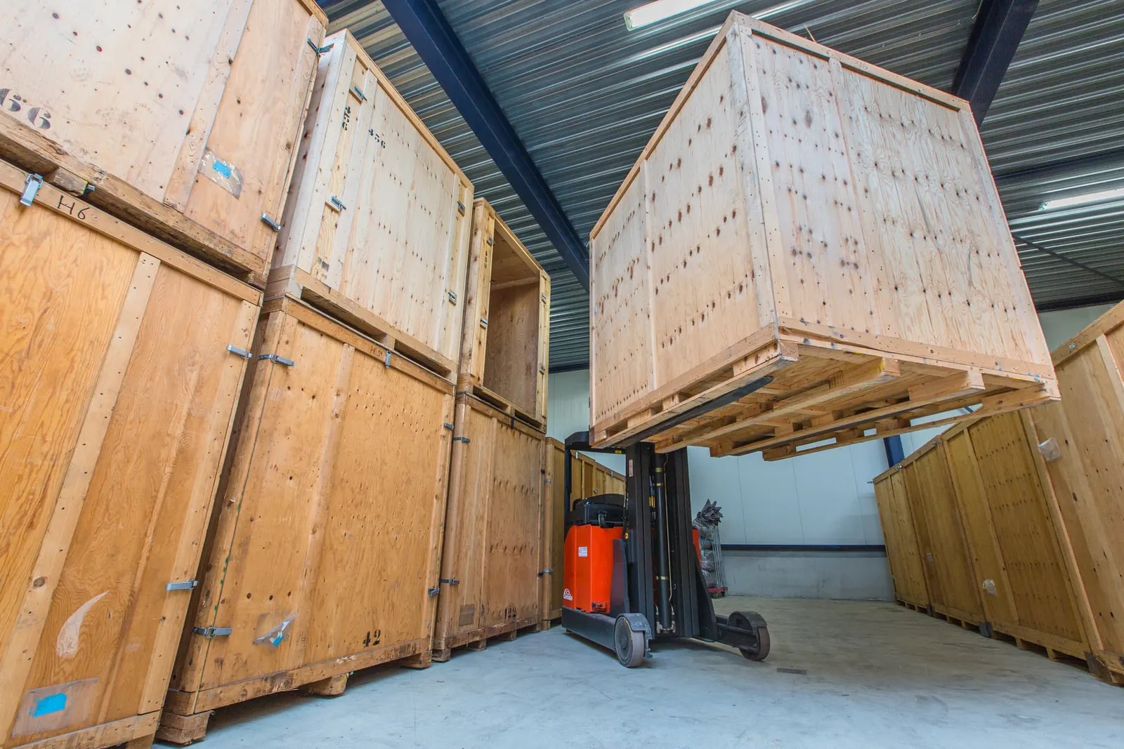 Heftruck tilt een houten opslagcontainer in het eigen magazijn